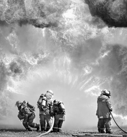 firefighter full gear emerging from smoky building